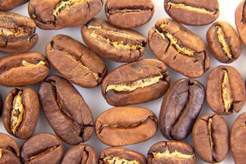 Detailed view of roasted coffee beans, displaying their cracked surfaces and earthy colors on a...