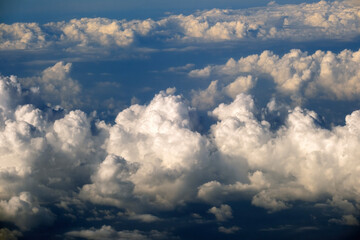 Aerial view from airplane window at high altitude of dense puffy cumulus clouds flying