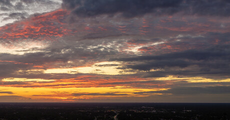 Colorful sunset sky over rural area. Setting sun behind vivid orange and yellow clouds