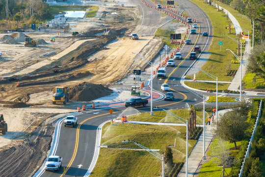 Driving traffic cars at roundabout intersection under construction. Building traffic circle on American road with moving cars