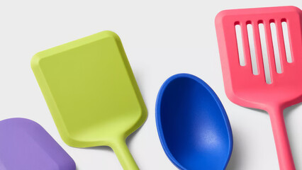 Colorful kitchen utensils arranged on a neutral background for cooking and baking activities.