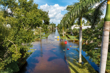 Flooded street in Florida after hurricane rainfall with road closed signs blocking driving of cars....