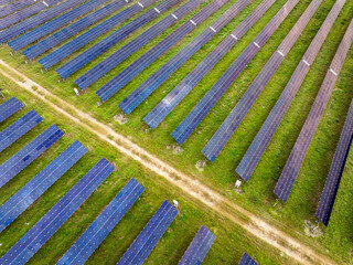 Industrial solar energy facility with uniform rows of panels converting sunlight into renewable electricity. Focus on sustainable development and emission-free energy generation