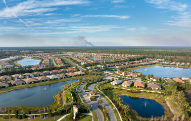 Fototapeta premium Prescribed fire smoke rising up over suburban neighborhood in Florida