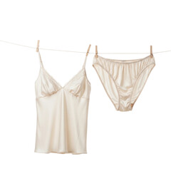 A delicate cream colored silk camisole and matching panties hang on a clothesline, secured by clothespins, suggesting laundry or intimate apparel care.
