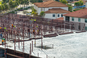 Workers assembling metal frame building at industrial construction site. Housing development in America. Real estate market in the USA