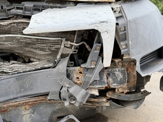 This minibus was significantly damaged as a result of a serious head-on collision. A seriously damaged grey minibus, which shows significant collision marks in the front and extensive rust marks.