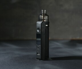 One electronic smoking device on dark table against grey background, closeup