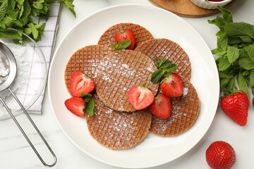 Tasty Dutch waffles (stroopwafels), mint and strawberries on white marble table, flat lay
