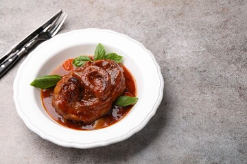 Traditional ossobuco dish with beef steak served on grey table, above view. Space for text