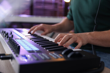 Man working with MIDI keyboard at table indoors, closeup