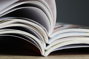 Different open magazines on wooden table, closeup
