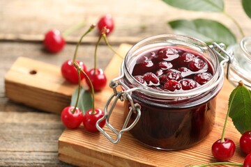 Tasty cherry jam and fresh fruits on wooden table, closeup