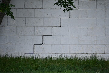 Diagonal cracks along mortar in cinder brick construction. Signs of foundation damage.