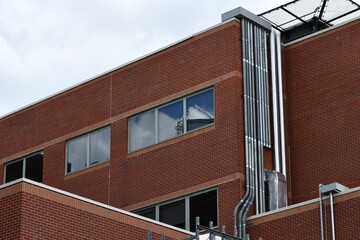 Large electrical conduits running up side of hospital. Red brick construction.