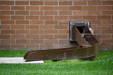 Large metal drain chute on brick building.