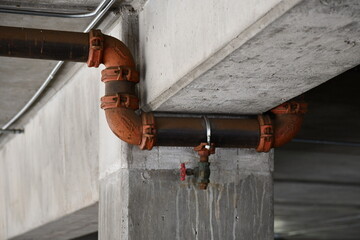 Large water pipes strapped to parking structure ceiling.