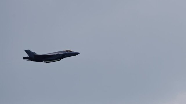 F-35 Lightning II Stealth Fighter Jet Banking Mid-Air with Open Weapon bays and Vapor Trails