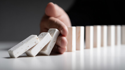 Decisive risk mitigation concept shown by executive hand halting domino chain to prevent cascading failure.
