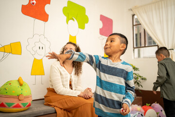 Hispanic boy throwing velcro balls at a target inside the classroom. Preschool activity promotes coordination, focus, and physical play during early childhood education