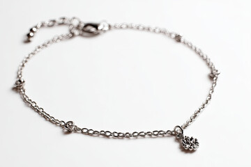 Delicate silver bracelet with intricate charm displayed on a soft white background, ideal for jewelry promotion
