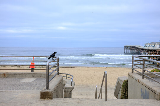 Access path guarded by metal barriers to shores of Pacific beach near public wooden Crystal pier in San Diego, California