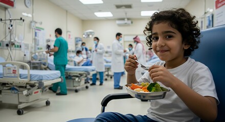 Young child enjoys a healthy meal in a hospital ward, surrounded by blurred medical staff and equipment.