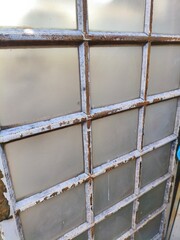 Rusty Vintage Industrial Window with Frosted Glass Panels and Weathered Metal Grid Frame Close-Up