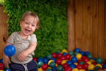 Baby having fun in the ball pit throwing a ball