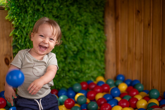 Baby having fun in the ball pit throwing a ball - Powered by Adobe