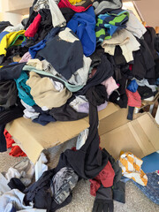 Pile of Unsorted Clothes on Cardboard Box – Lost and Found, Donation, or Recycling Concept. fast fashion. background