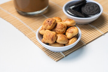 Golden Mini Pastries and Chocolate Cookies with Beverage on Bamboo Mat for Sweet Snack or Breakfast