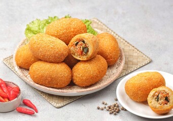 Kroket kentang. Croquettes are lumps of finely mashed potatoes filled with seasoned minced meat and mixed with vegetables such as carrots or green beans. The croquettes are coated with beaten egg and 