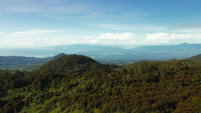 Forested slopes of Mount Apo unfold toward Davao Gulf under clear blue sky, revealing layered ridges, coastal plains and distant volcanic silhouettes.