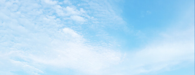 A clear blue sky with soft, scattered white clouds, creating a calm and peaceful atmosphere.

