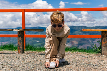 Colombian boy tying his shoelaces outdoors on a sunny day, childhood moment of independence and...