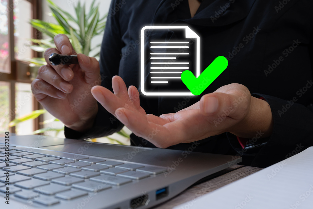 Poster businesswoman's hand in front of a computer holding a virtual document icon with a check mark