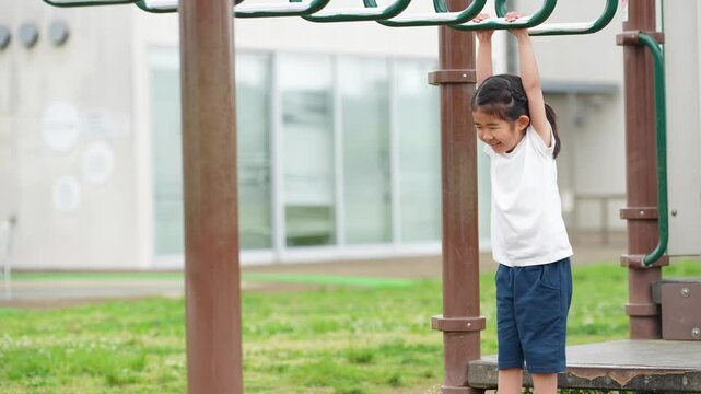 公園の雲梯で遊ぶ女の子