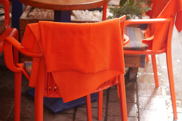 Bright orange towel draped over chair in a cozy cafe