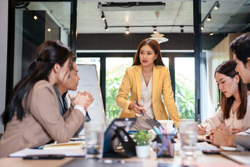 Young female ceo and business people discussing company presentation at boardroom table.