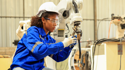 African american engineer woman fixing and testing an Artificial Intelligent welding robotic...