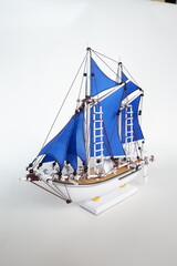 Miniature of a Traditional sailing boat made from wood and has blue sail