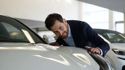 Caucasian man buyer client auto automobile salon choose touching headlight car hood vehicle buying...