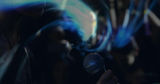 Singer singing into mic during music gig causing pulsing blue swirl revealing audience