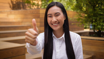 Asian Korean Japanese Chinese woman showing thumb up sign approval like smiling female girl...