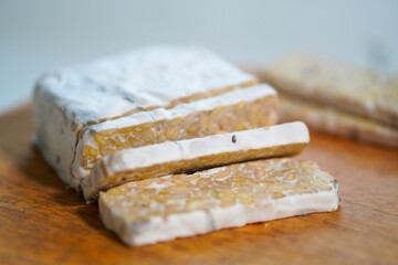 Closeuo, Tempeh that has been cut into pieces on a wooden cutting board