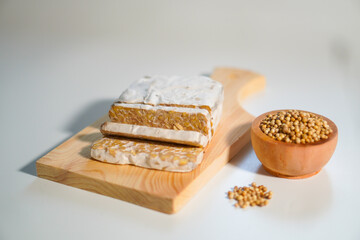 Tempeh that has been cut into pieces on a wooden chopping board with added coriander as a complement.