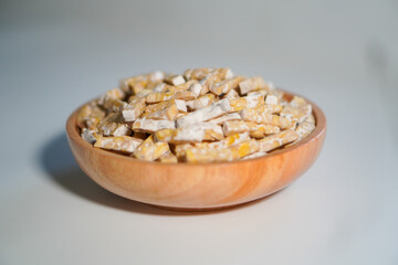 Tempeh that has been cut into small pieces is placed in a wooden bowl.