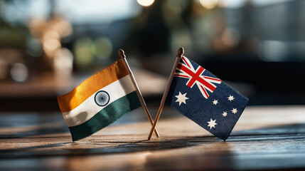 Diplomatic Flags of India and Australia: Close-up of the Indian and Australian flags gracefully crossed on a wooden surface, symbolizing the nations' collaborative spirit.