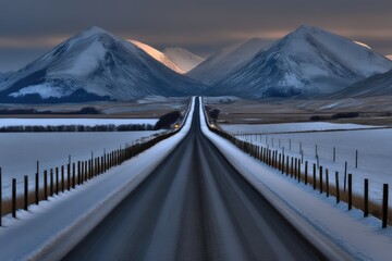 Long straight winter road leading to snow covered mountain range in the distance